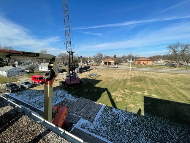 Construction site with crane, vehicles, and building on a clear day.