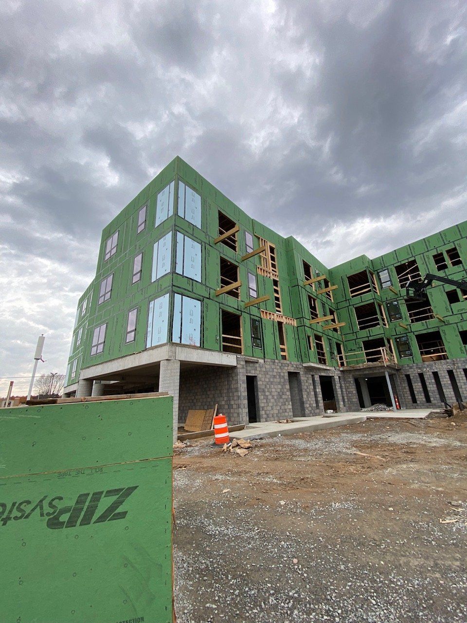 Building under construction, wood framing and concrete foundation, overcast sky.
