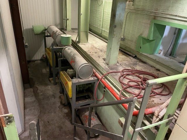 Industrial equipment with cylindrical drums, in a factory hallway. Red hose, gray, green, and yellow colors.