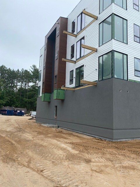 Modern building under construction with gray and white facade and wooden supports.