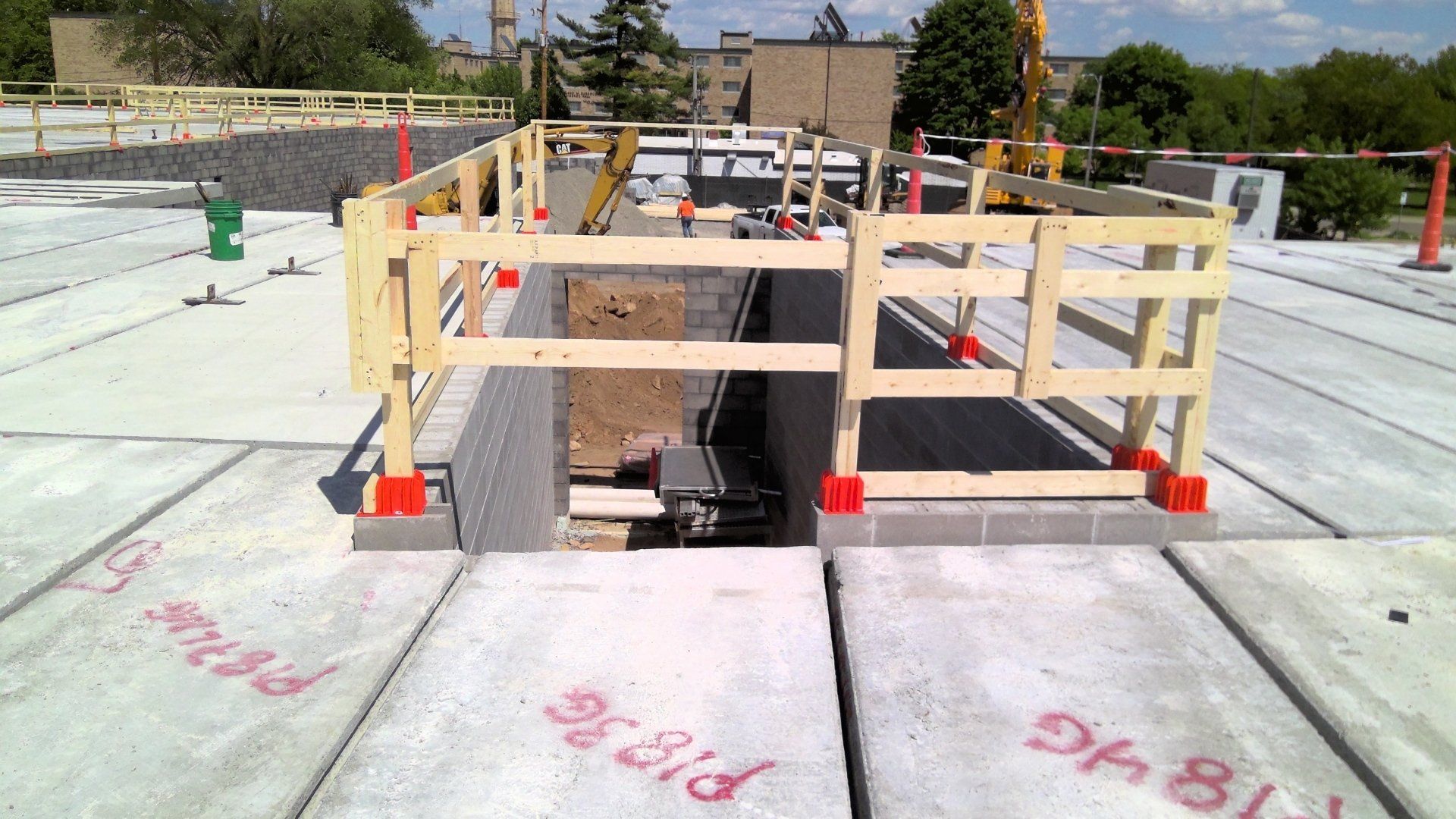 Construction site with safety railings around an open pit on a concrete surface.