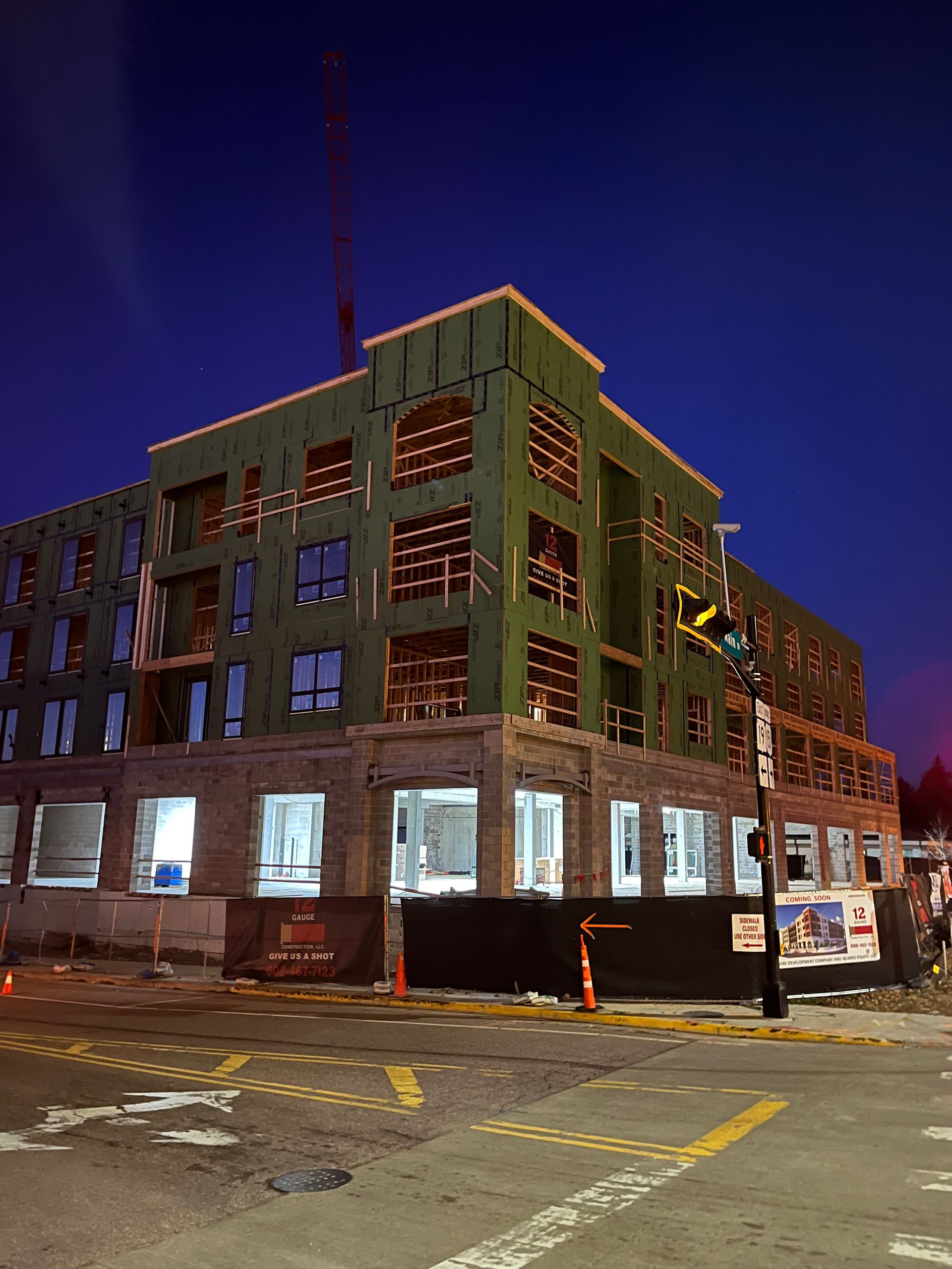 Building under construction at night, framed by dark blue sky, with wood frame and exposed windows.
