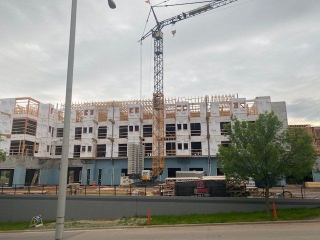 Building under construction with a crane, cloudy sky.