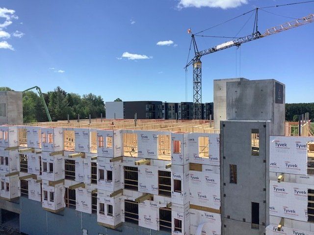 Construction site with partially built buildings, crane, and blue sky.