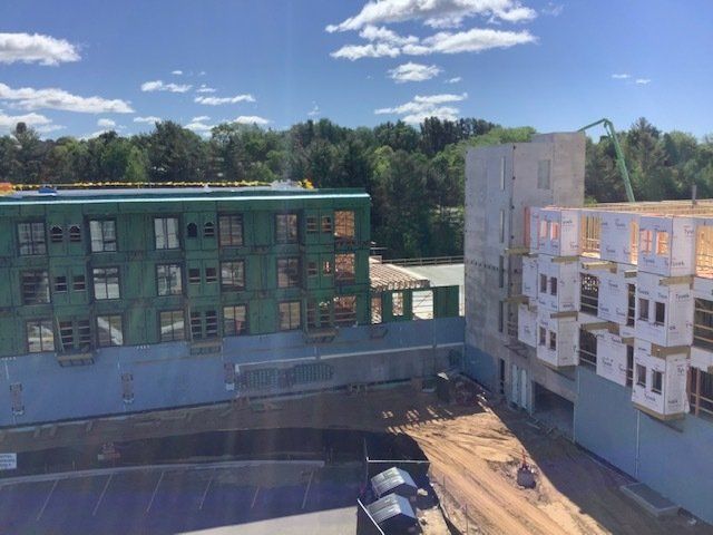 Construction site with two partially built multi-story buildings on a sunny day.