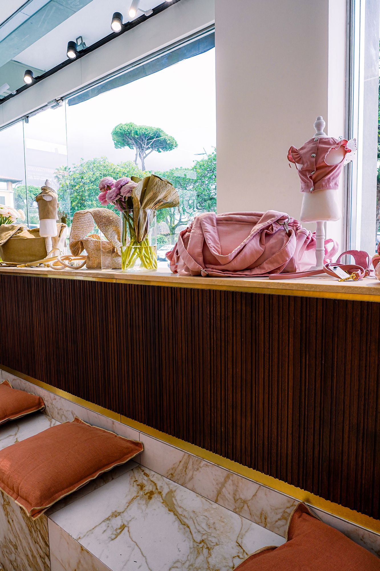 Elegante bancone da caffè con decorazioni rosa, composizioni floreali e posti a sedere con piano in marmo accanto a grandi finestre.