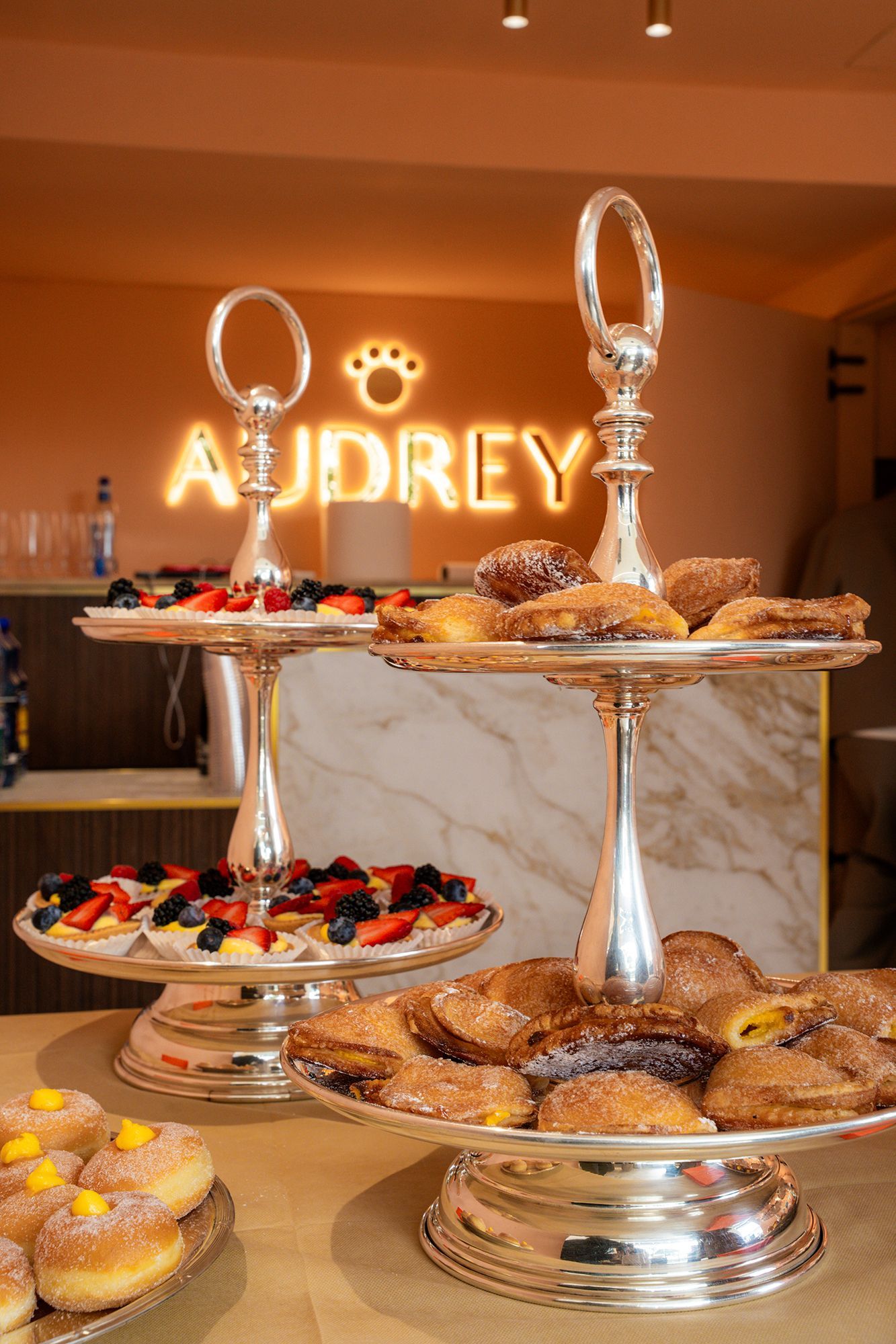 Buffet di dolci con torte e pasticcini su alzatine d'argento, con la scritta 