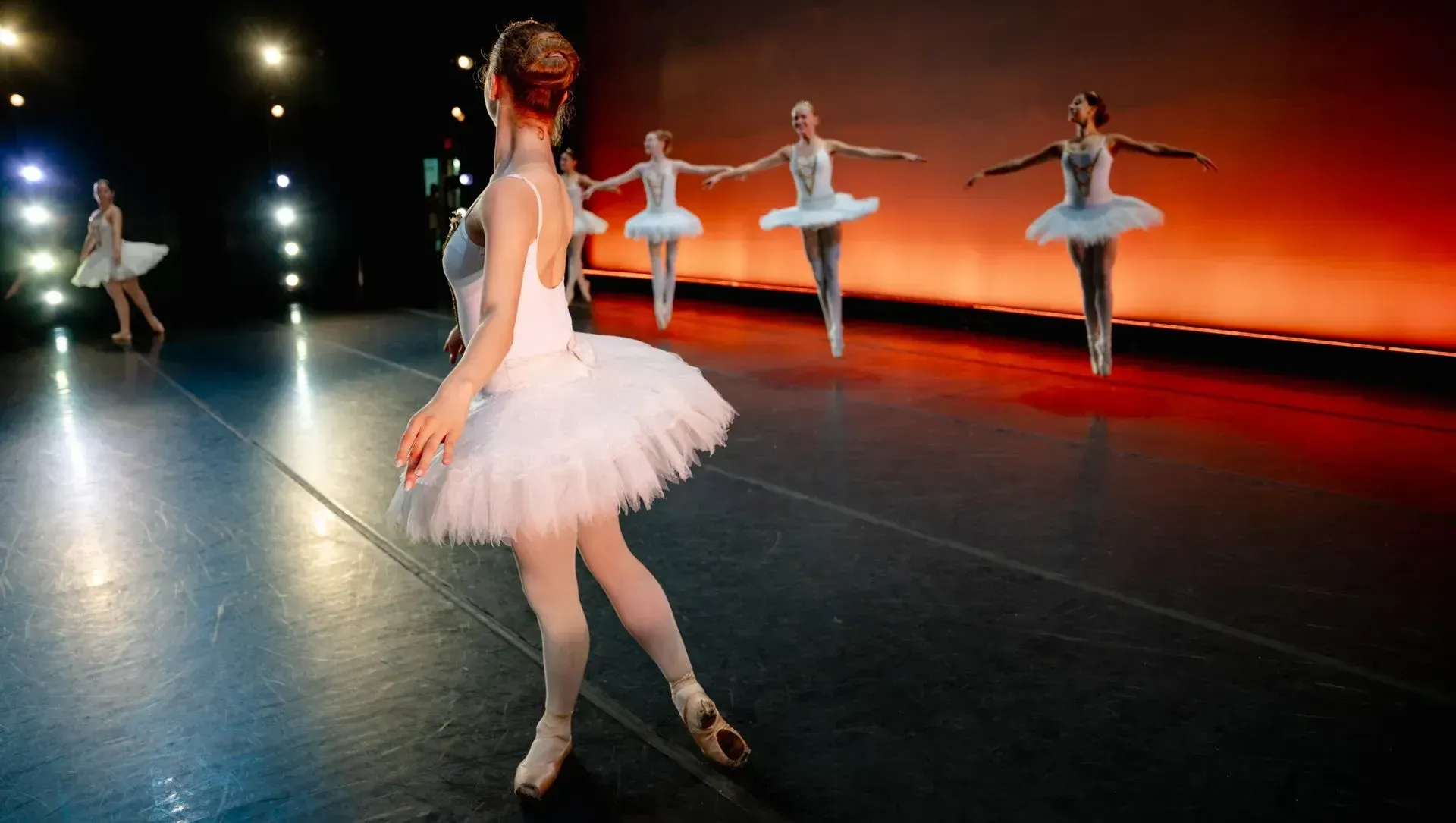 A group of young ballerinas are dancing on a stage.