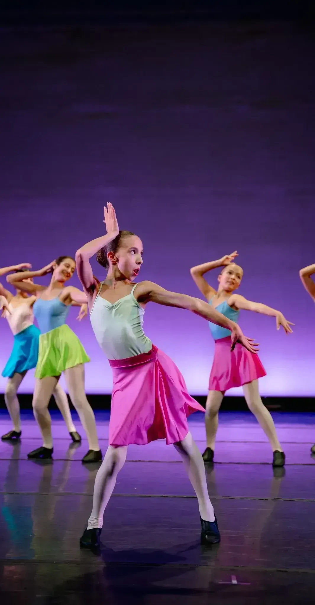 A group of young girls are dancing on a stage.