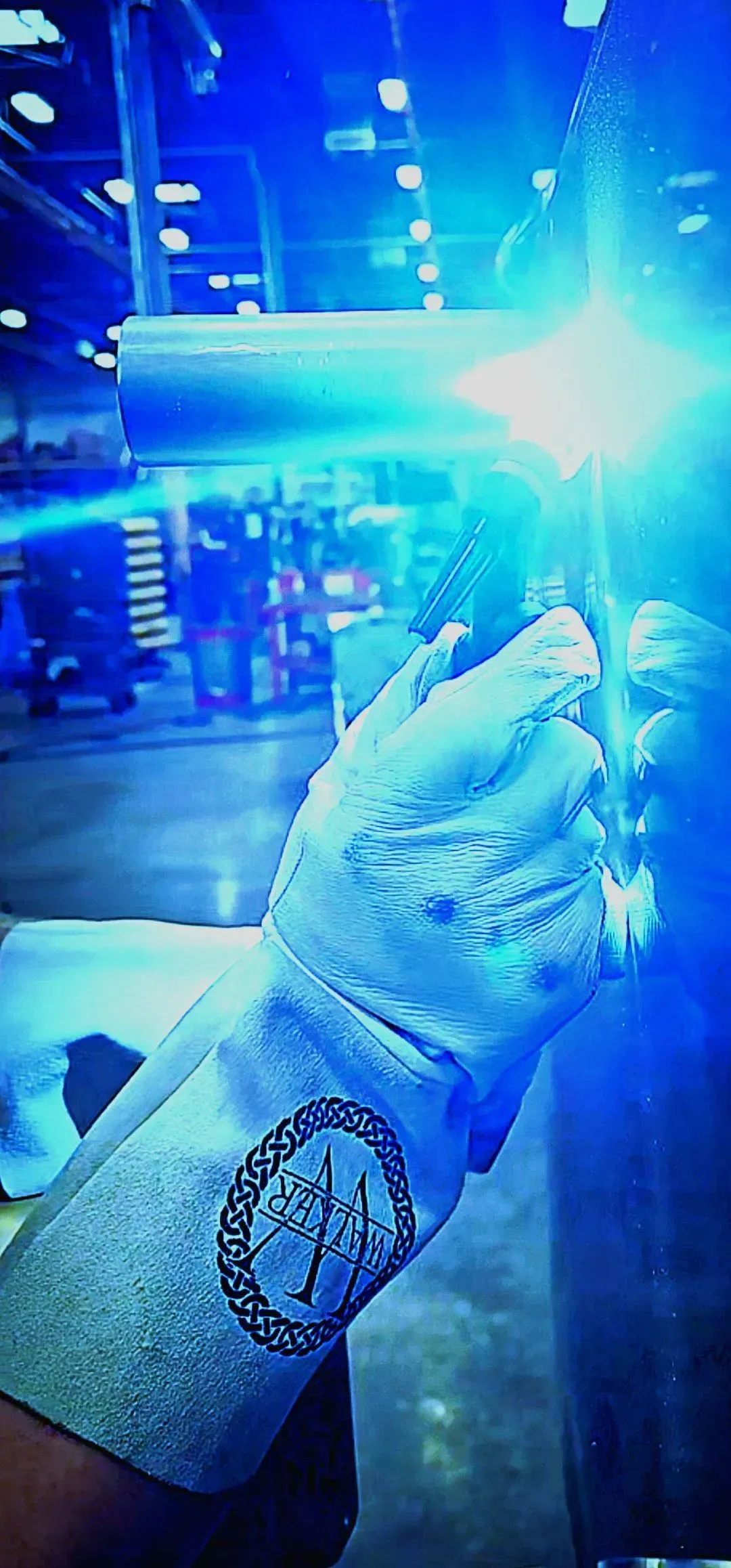 A person wearing a welding glove is welding a piece of metal.