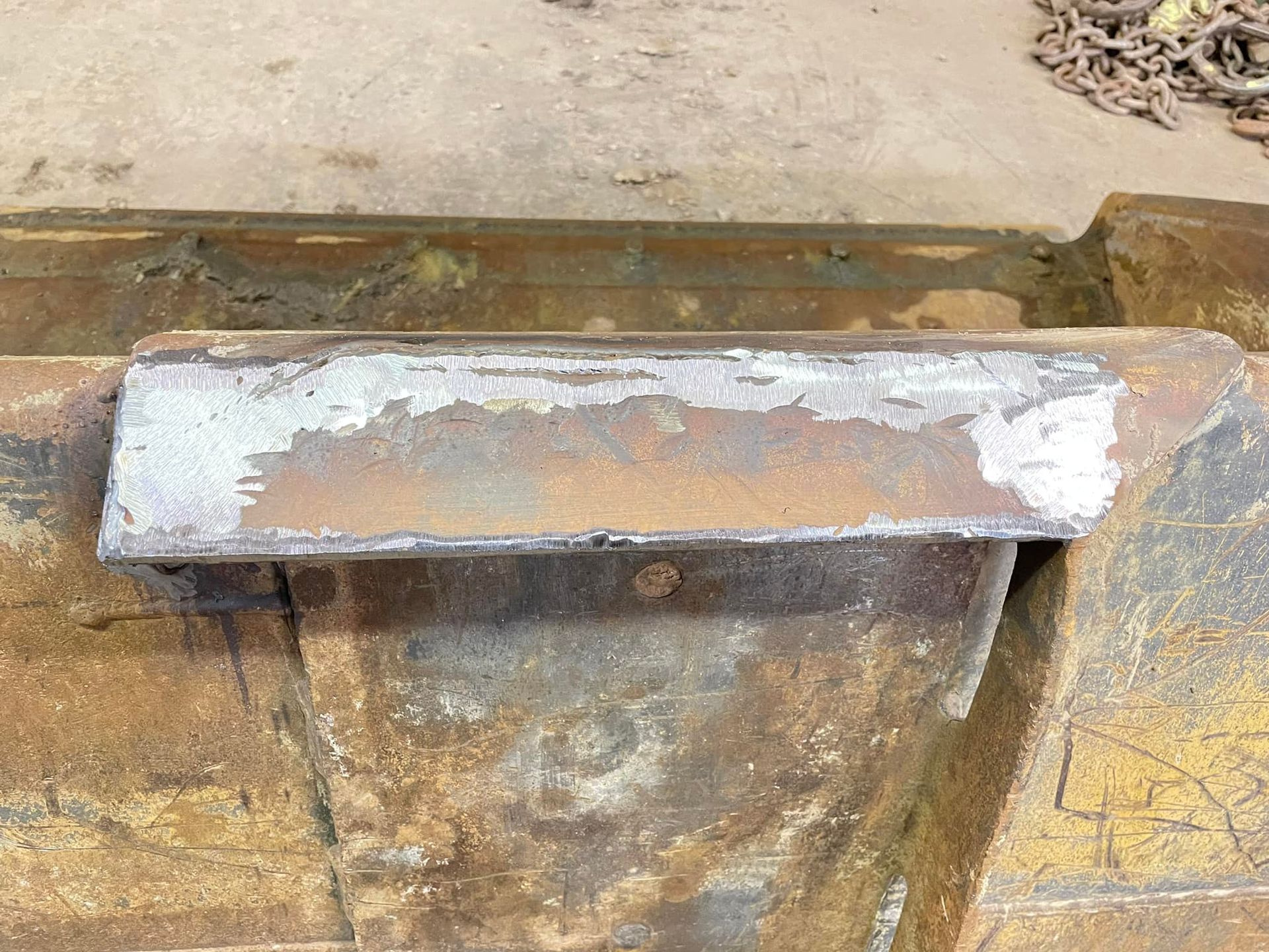 A piece of rusty metal is sitting on top of a concrete surface.