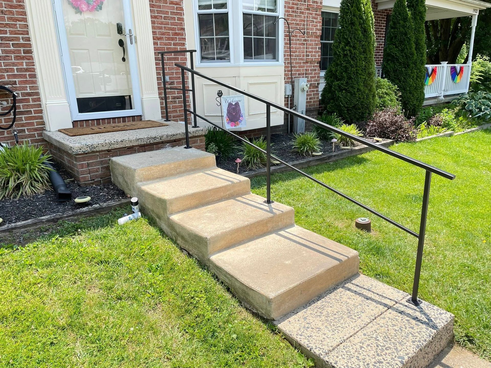 A set of stairs leading up to a brick house with a metal railing.