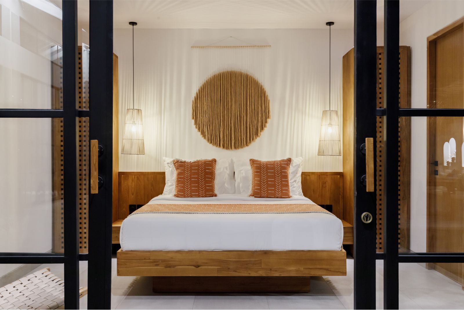 Stylish bedroom with a wooden bed, woven wall art, and soft white curtains