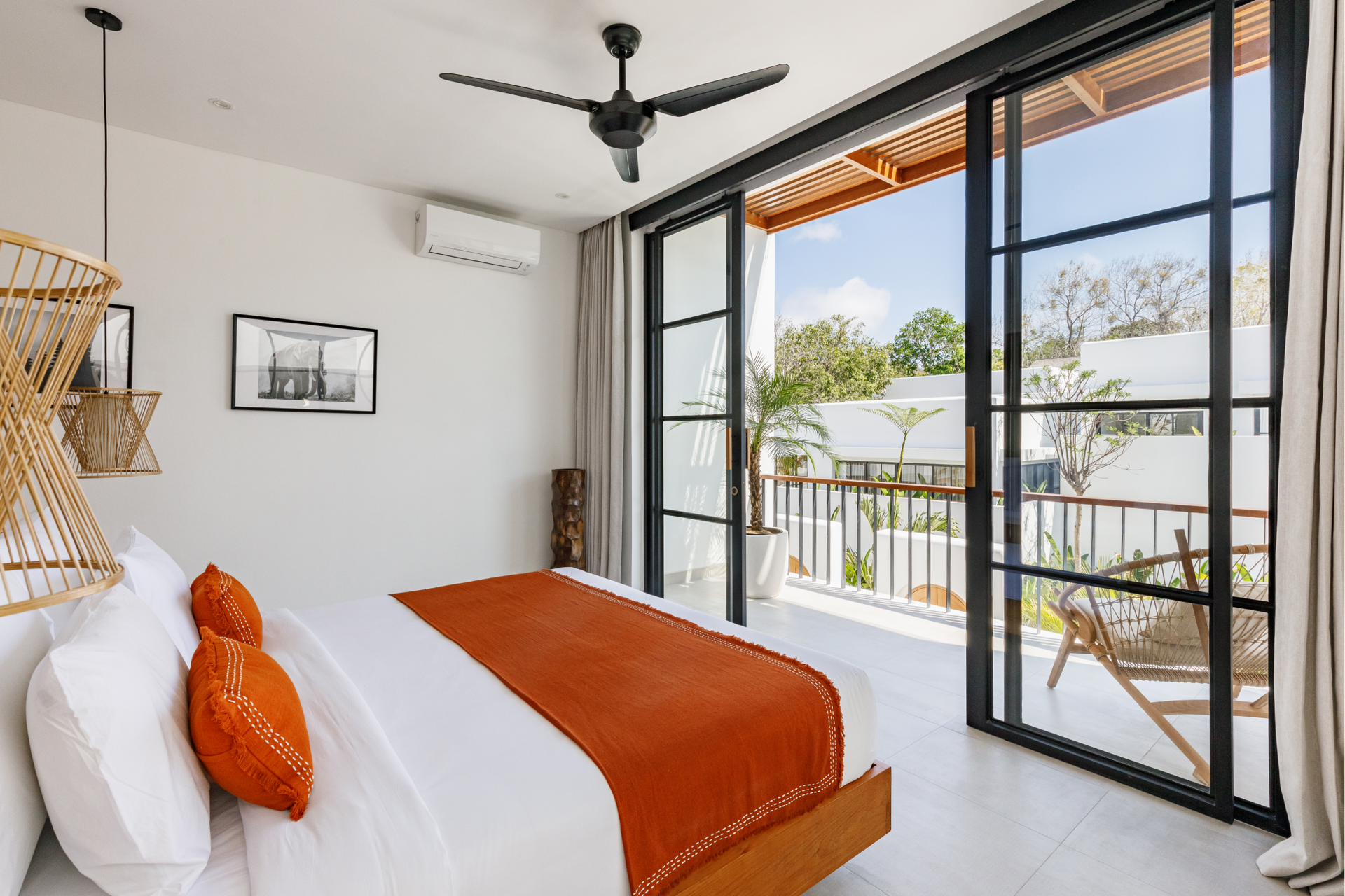 Bright bedroom with orange accents, ceiling fan, and large sliding doors to a balcony.