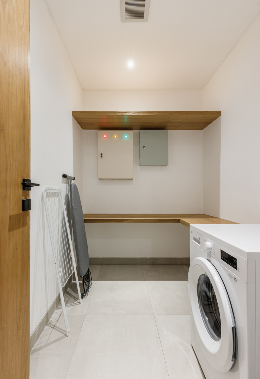Small laundry room with white walls, shelves, and a front-loading washer beside a drying rack.