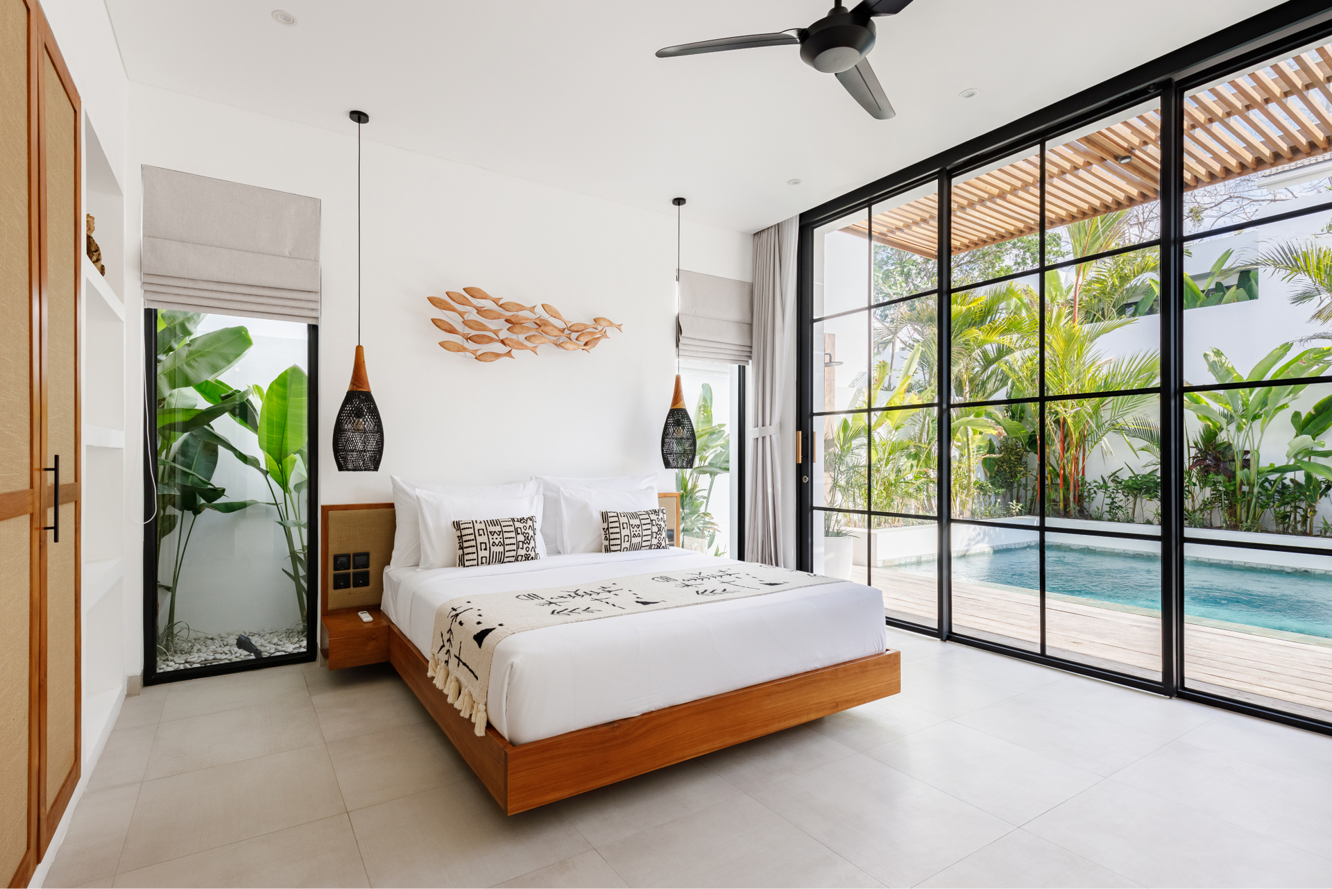 Bright bedroom with a bed, ceiling fan, and large glass doors opening to a pool patio