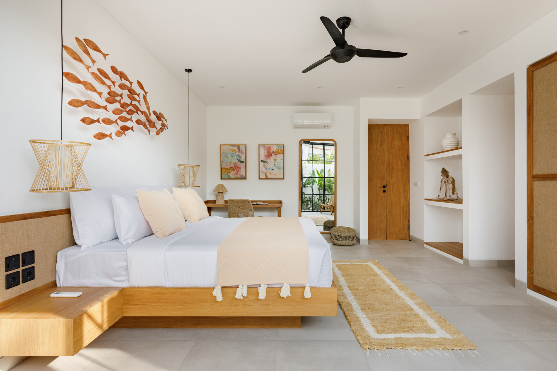 Bright modern bedroom with white bedding, wood accents, ceiling fan, and a small desk by a window.