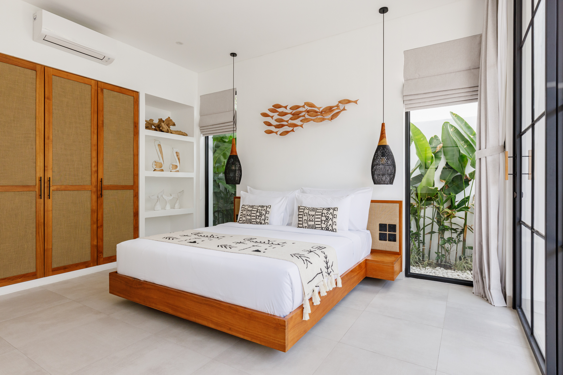 Bright modern bedroom with a wooden bed, white decor, open shelving, and large windows.