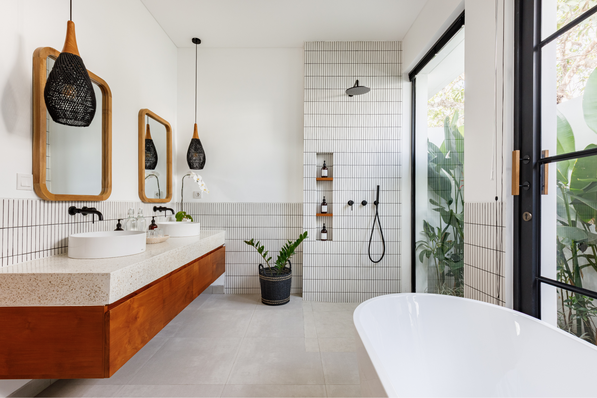 Modern bathroom with wood vanity, large mirrors, walk-in shower, and freestanding tub by floor-to-ceiling windows