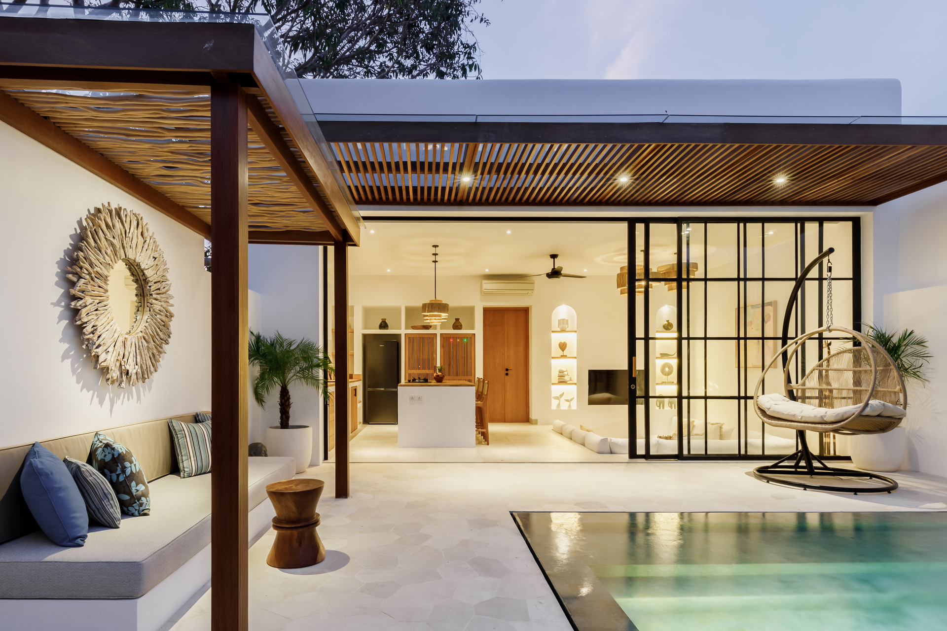 Modern patio with pool, open living space, and warm wood accents at dusk