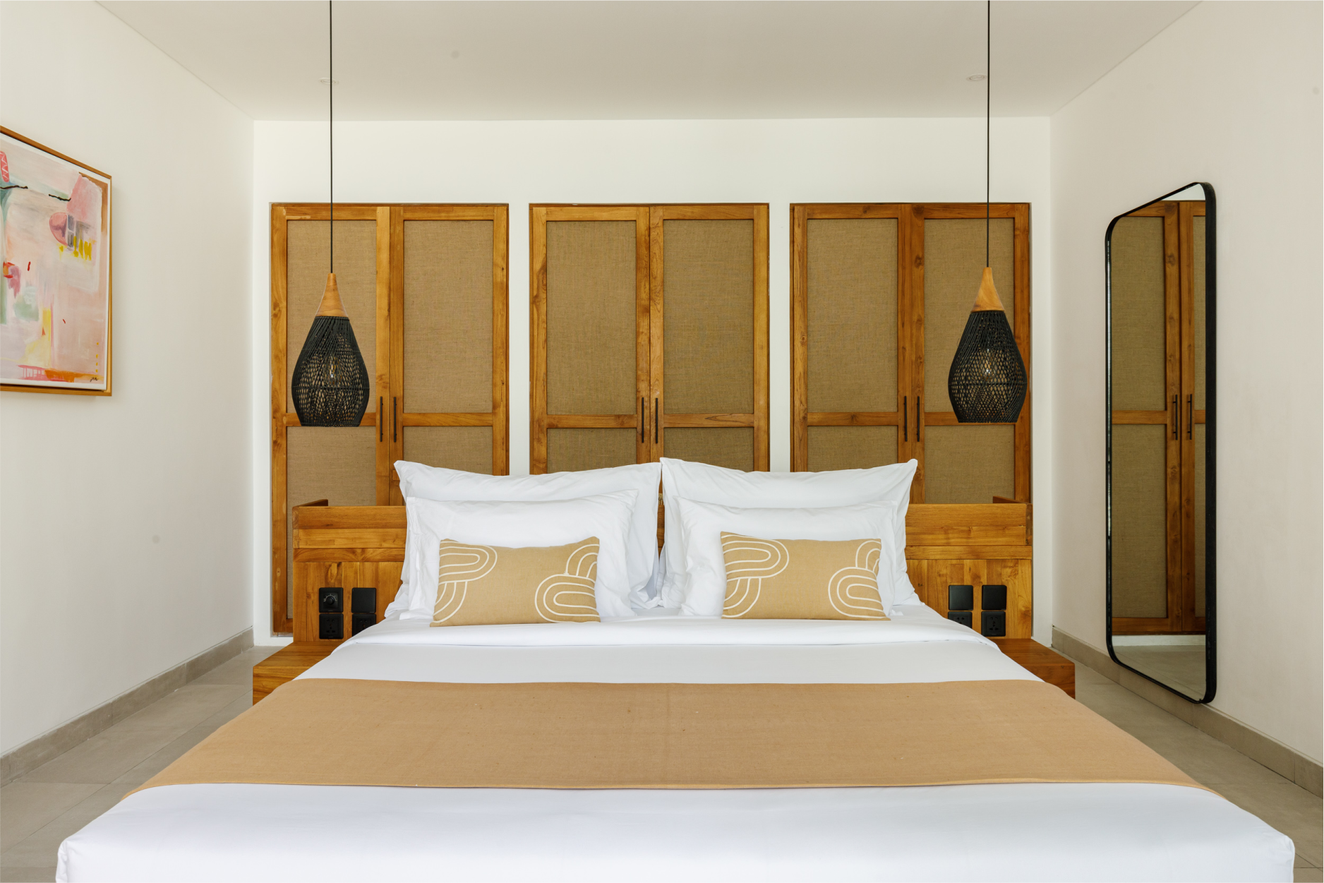 Minimal bedroom with a white bed, tan bedding, wooden screens, and wall lamps