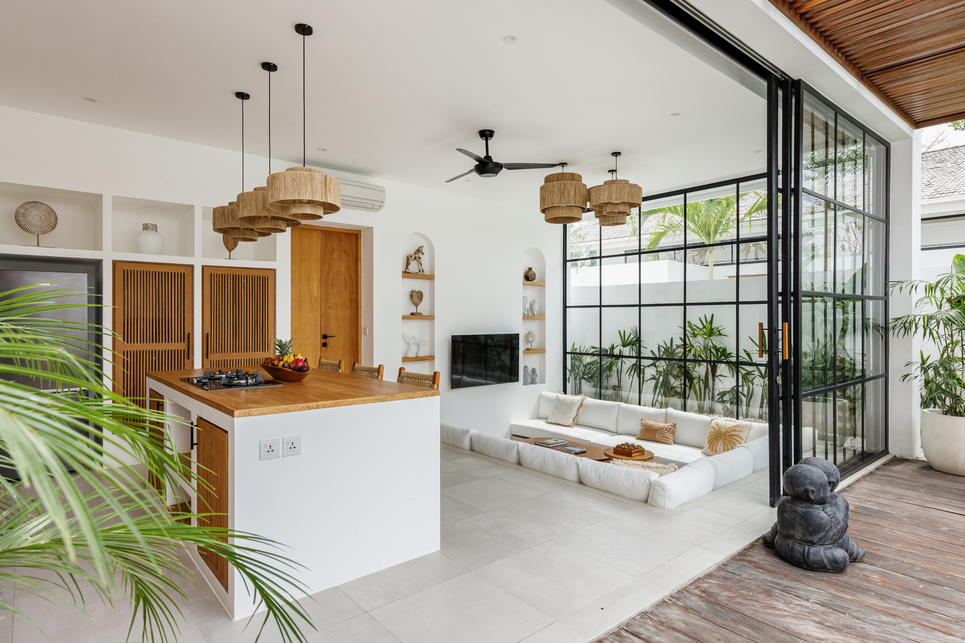 Bright modern patio with white seating, wood bar, rattan pendant lights, and black-framed glass doors