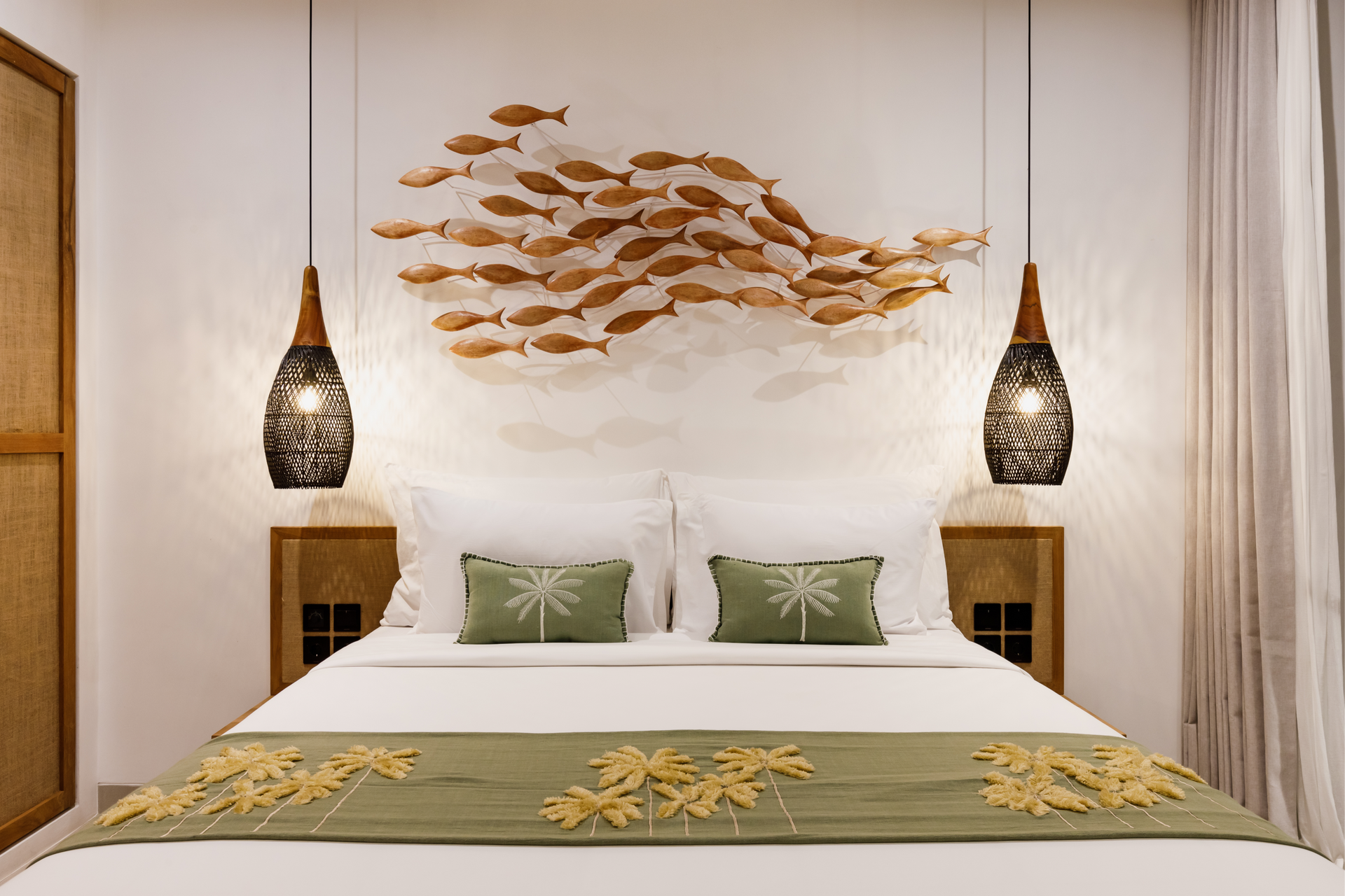 Modern bedroom with a large bed, green accents, hanging lamps, and fish wall art on a light wood backdrop