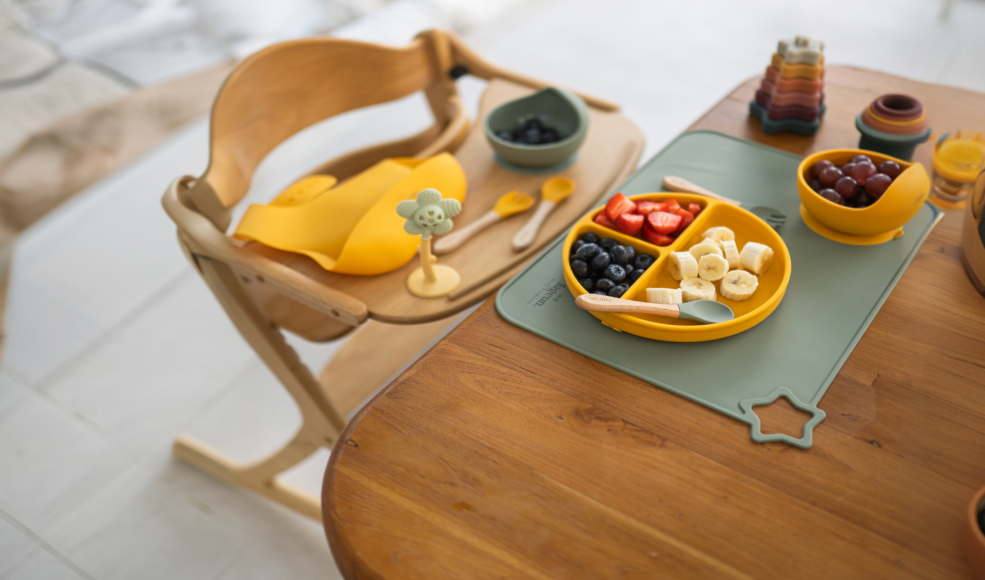 Wooden toy tea set with yellow plates and cups on a small table and chair
