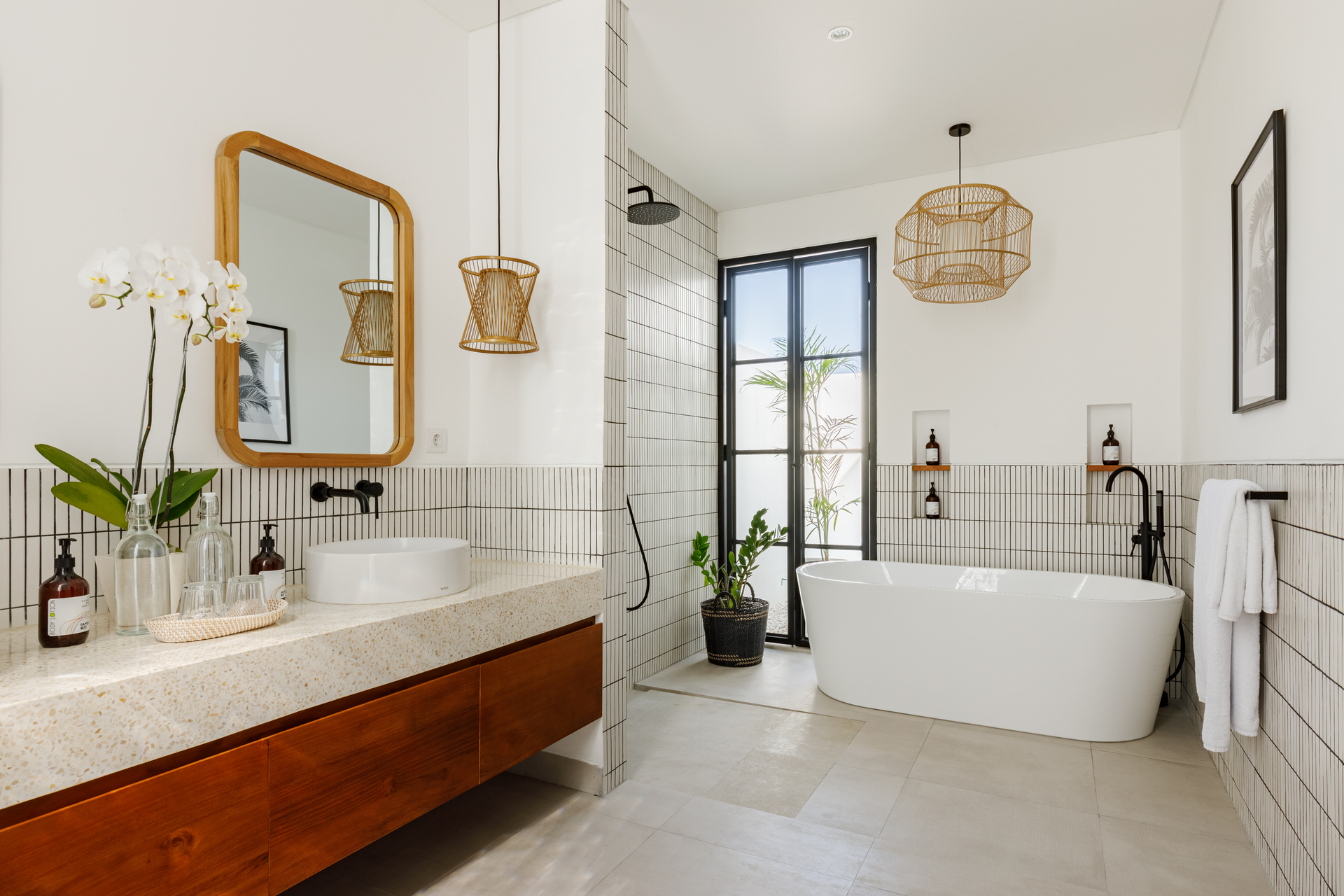 Modern bathroom with freestanding tub, wood vanity, large mirror, and black-framed shower door
