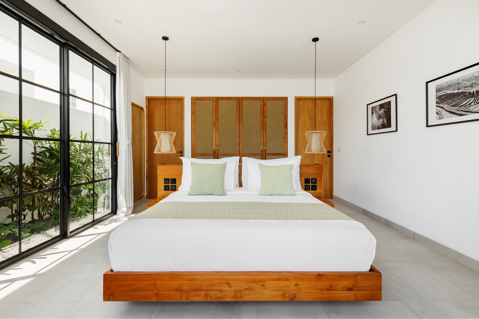 Bright modern bedroom with a wooden bed, large windows, and white walls