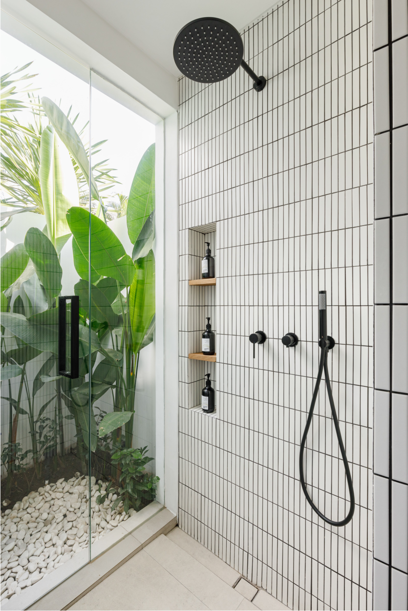 Modern tiled outdoor shower with black fixtures beside lush tropical plants