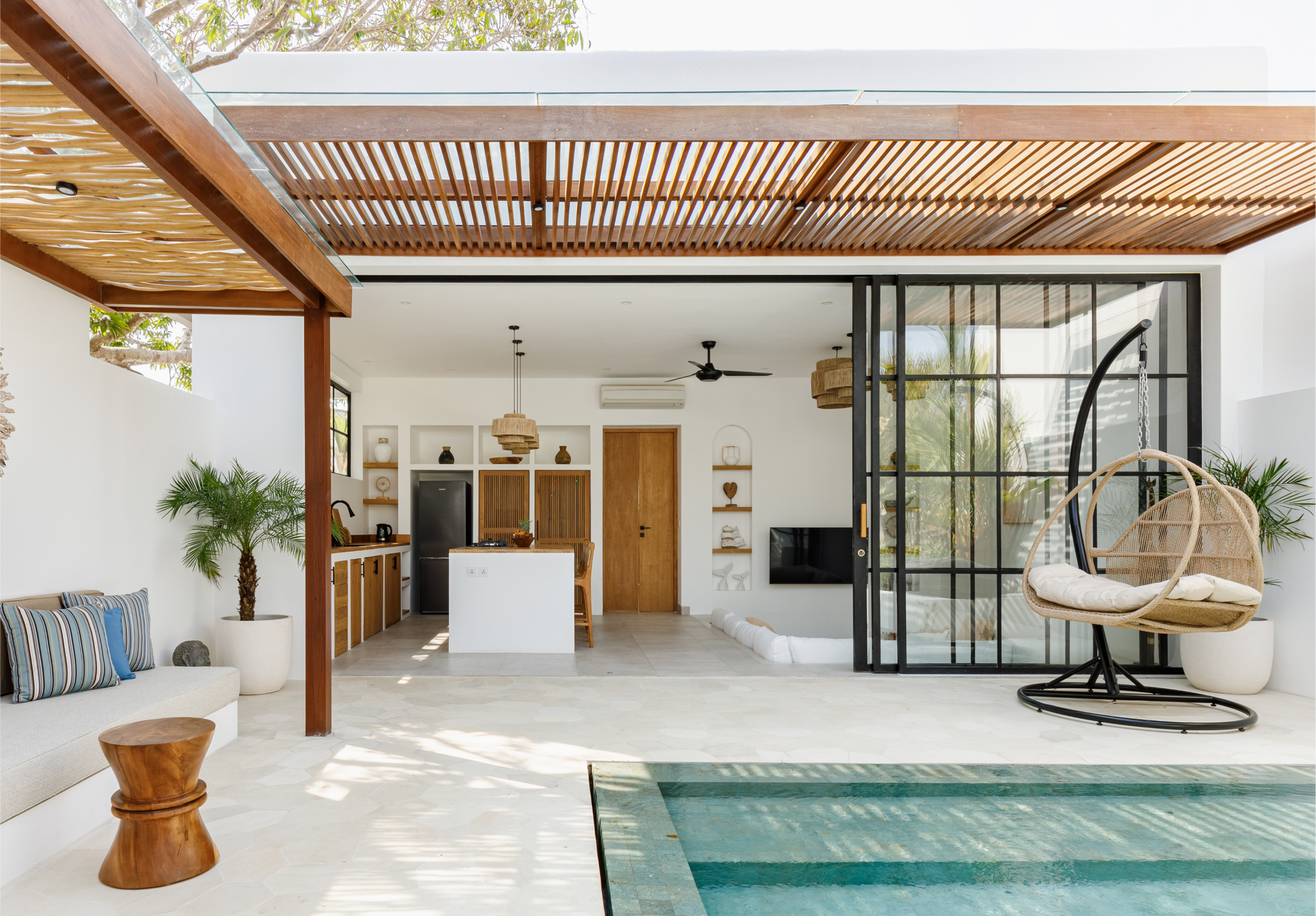 Modern open-air patio with pool, wood pergola, sliding glass doors, and white kitchen interior