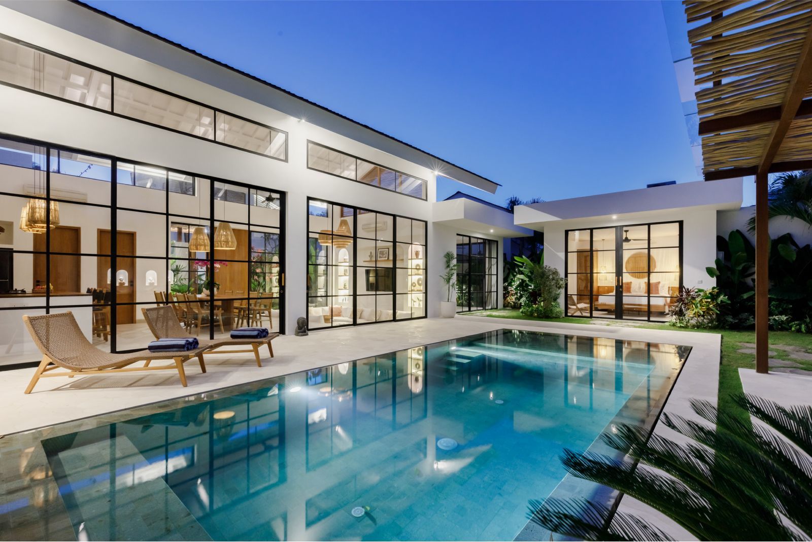 Modern house courtyard with a turquoise swimming pool at dusk