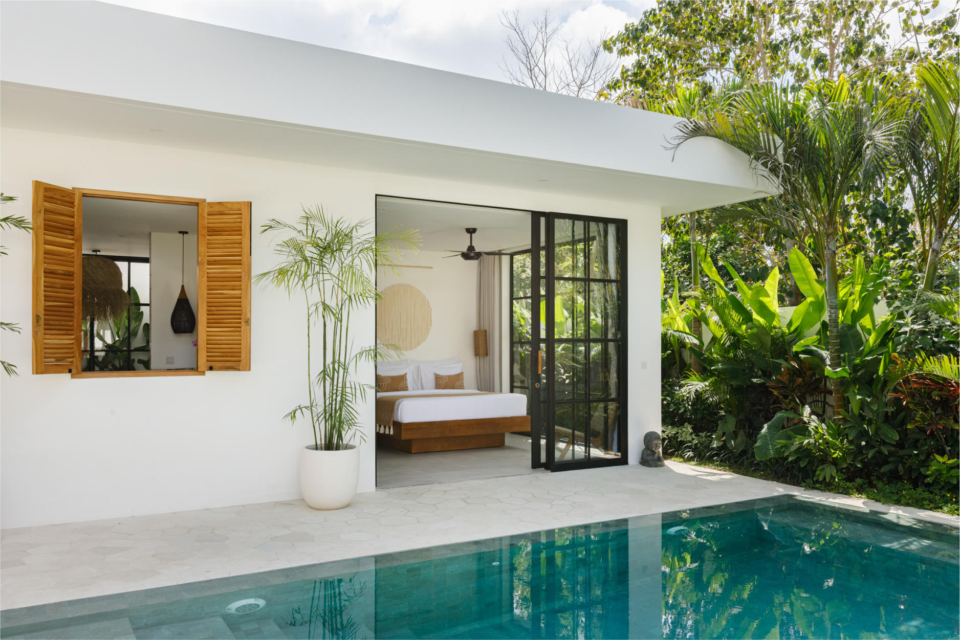 Modern white villa patio with a turquoise pool, open wooden shutters, and a glass door overlooking lush greenery
