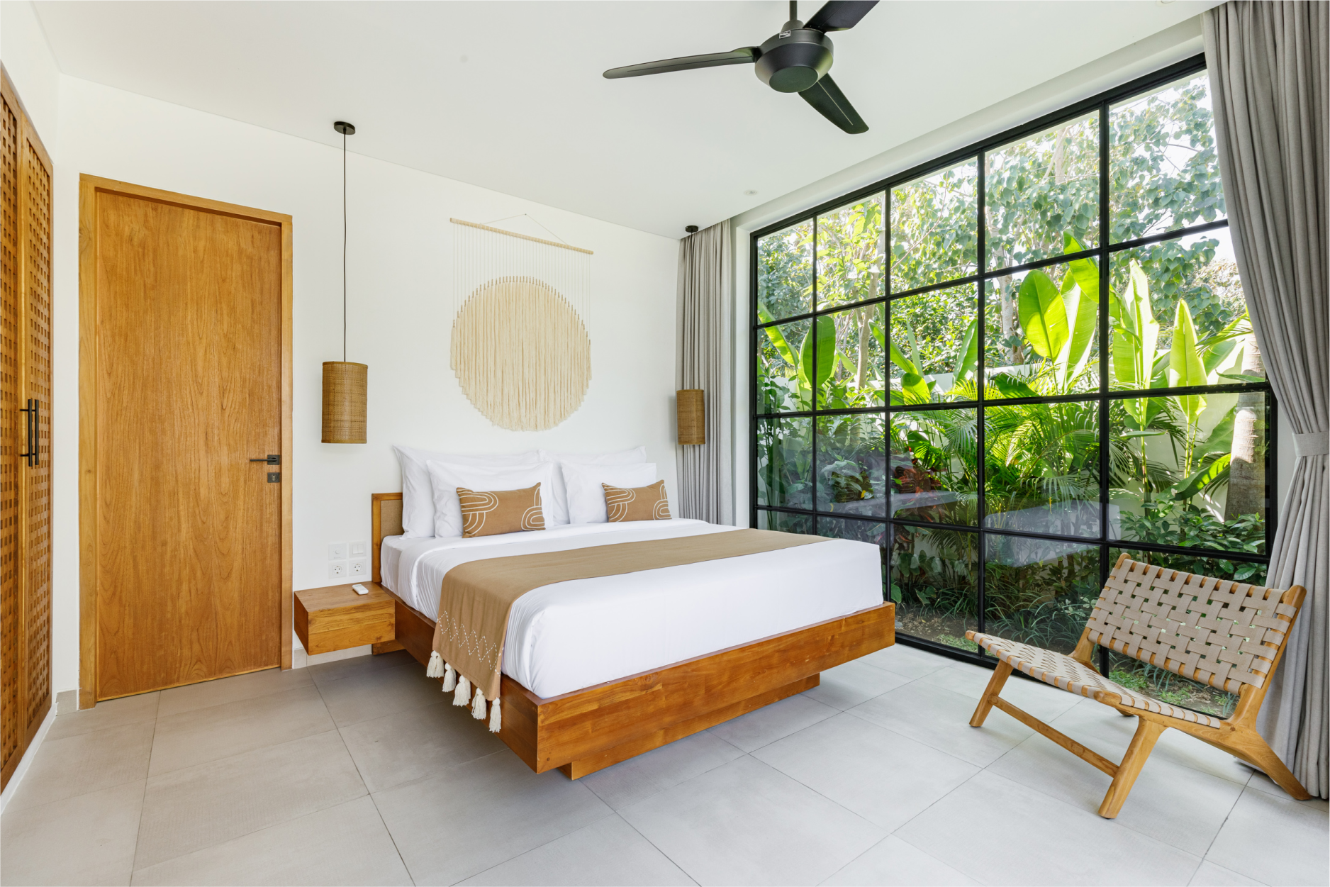 Modern bedroom with a wood bed, large window, ceiling fan, and woven chair seat