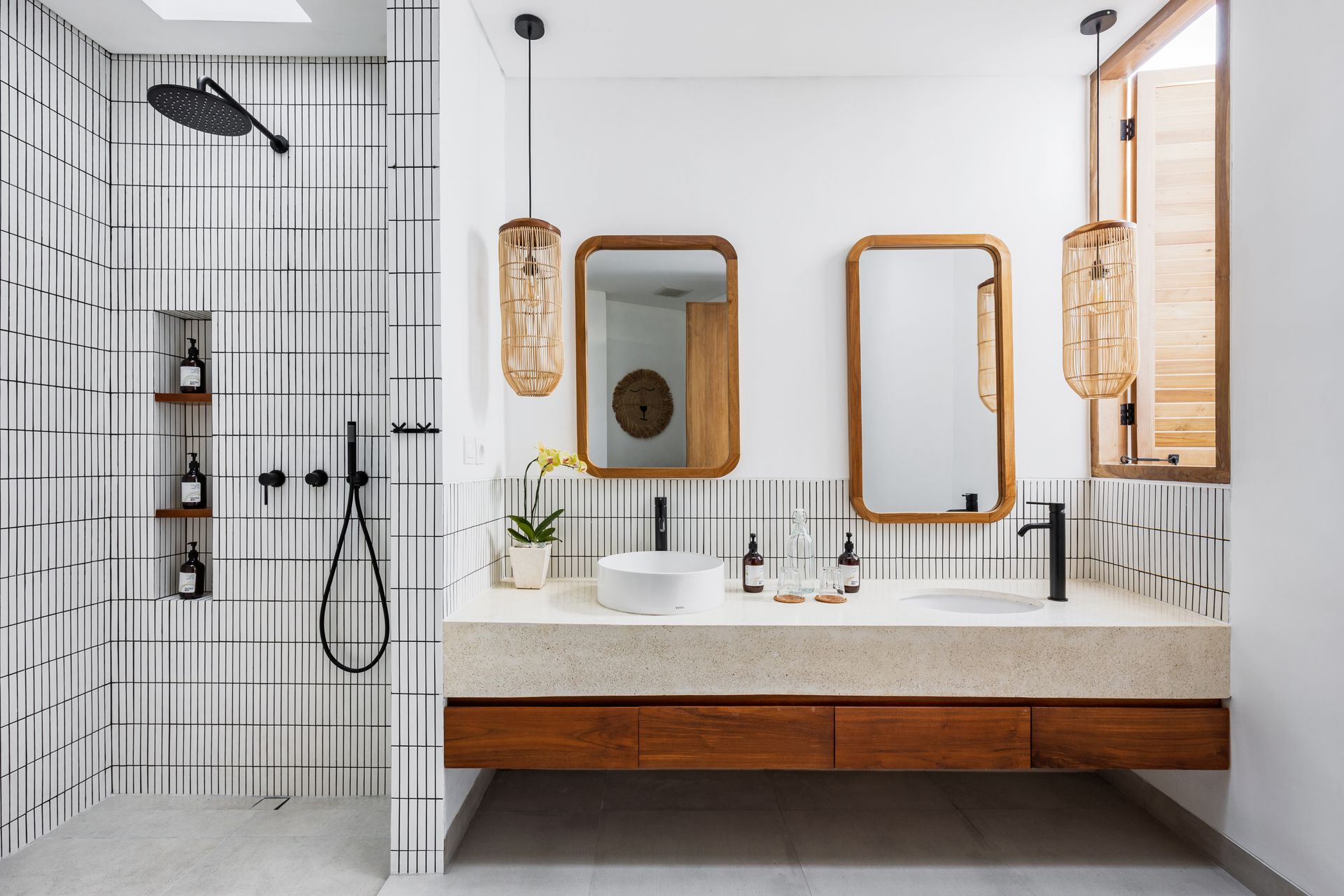 Modern bathroom with white tile walls, wood vanity, round mirror, and black shower fixtures