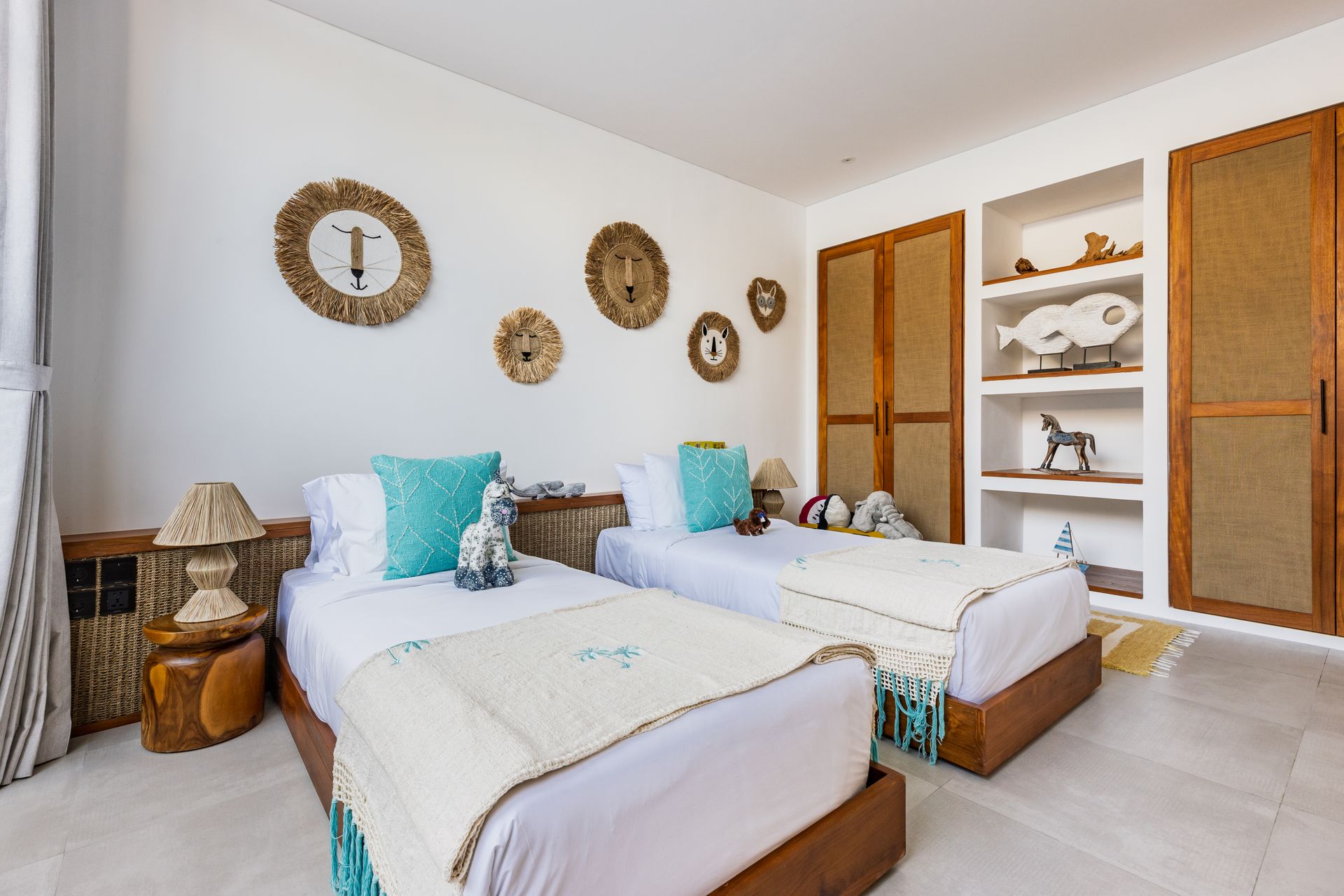 Bright bedroom with two twin beds, turquoise accents, wicker decor, and open shelving