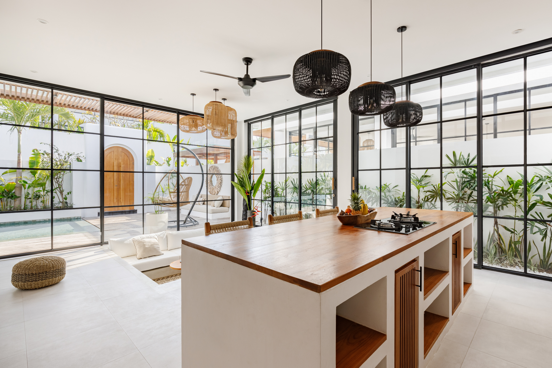 Bright modern kitchen with island, black pendant lights, and large glass doors opening to a patio