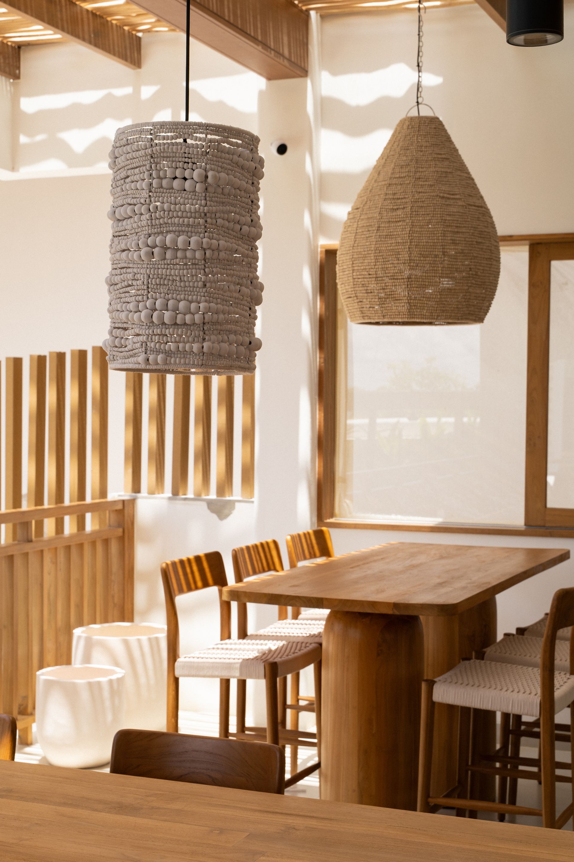 Cozy dining nook with wooden table and chairs, woven pendant lights, and warm natural light