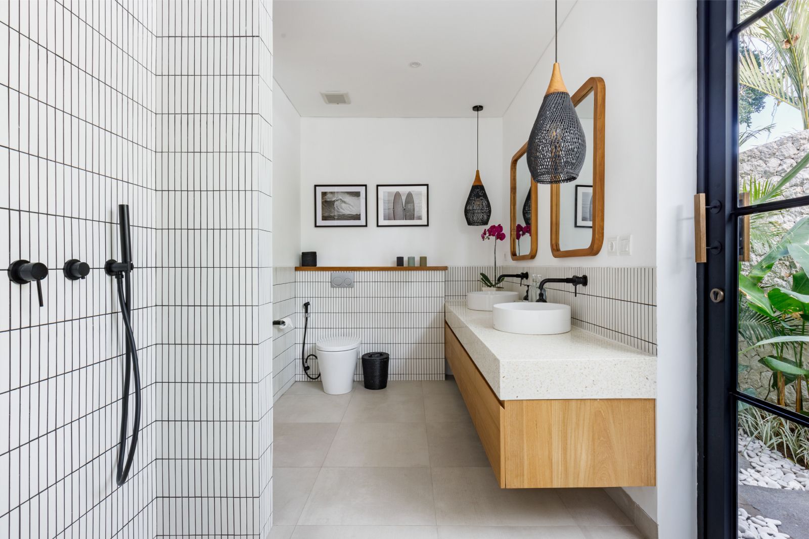 Modern bathroom with shower, wood vanity, round mirror, and light tile walls