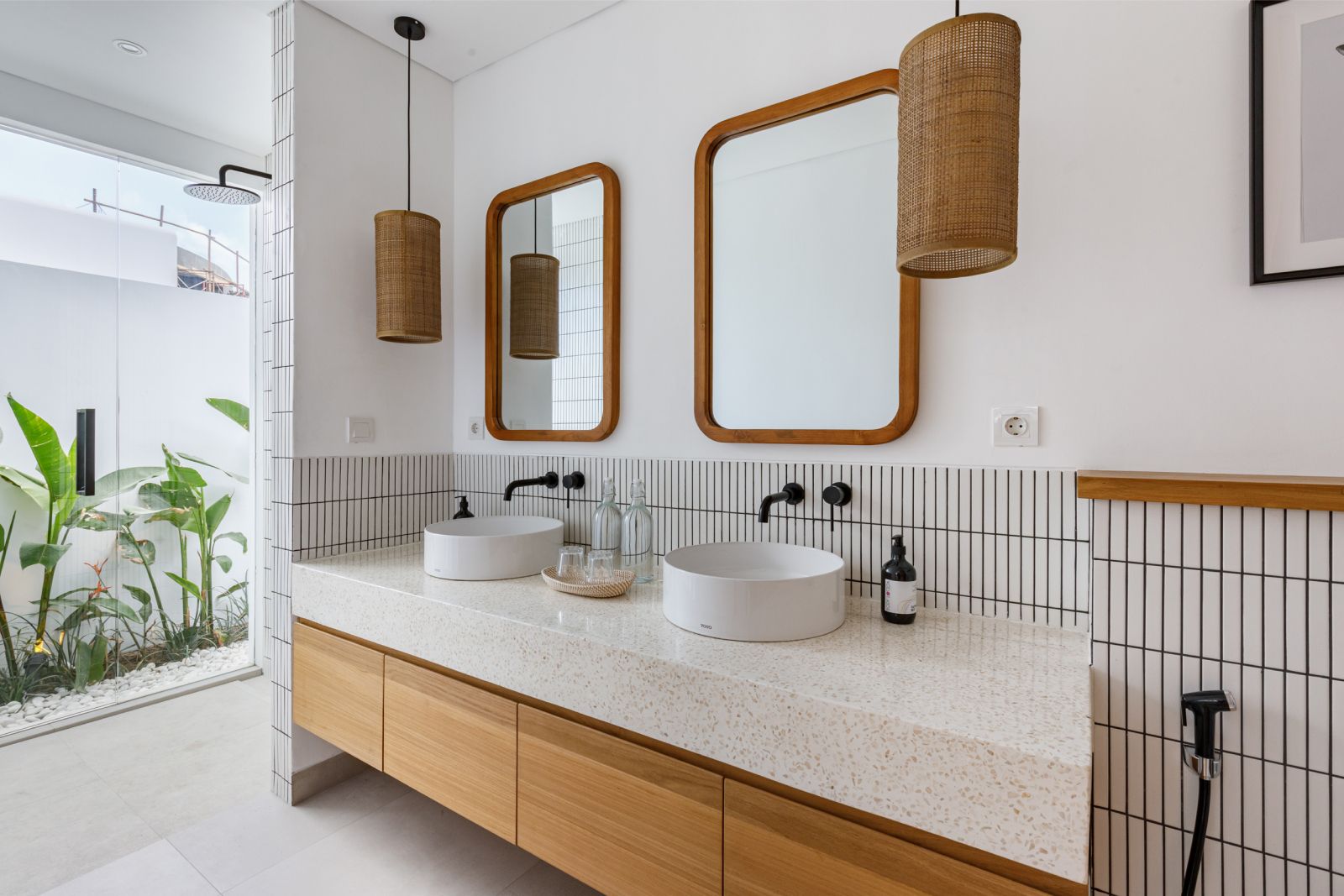 Modern bathroom vanity with twin sinks, wood cabinets, wicker pendant lights, and a large mirror