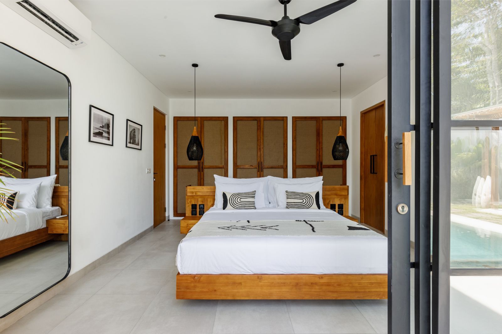 Modern bedroom with wooden bed, built-in wardrobe, ceiling fan, and sliding glass door to balcony