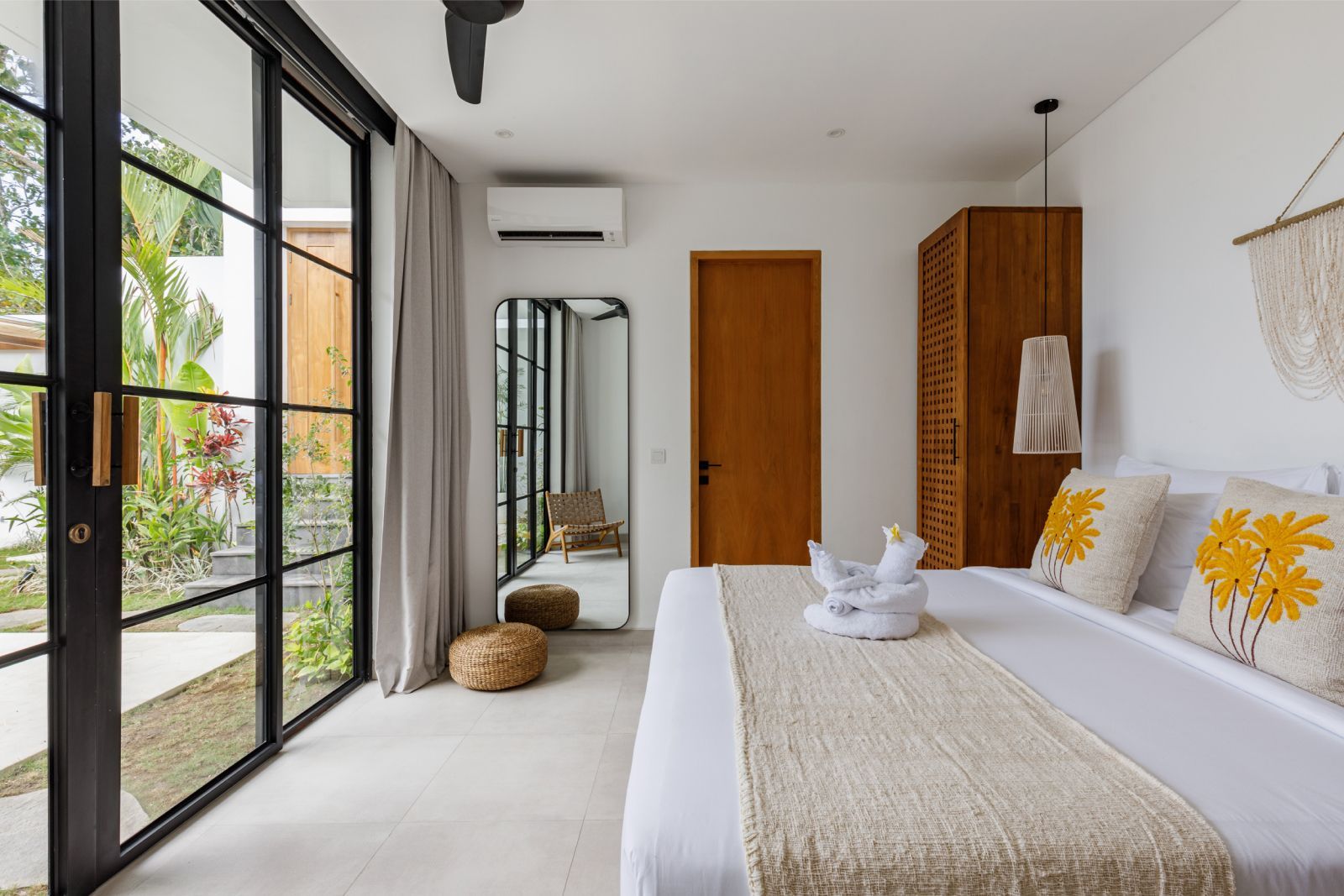 Bright bedroom with a large bed, wooden door, mirrored closet, and floor-to-ceiling glass doors to a patio