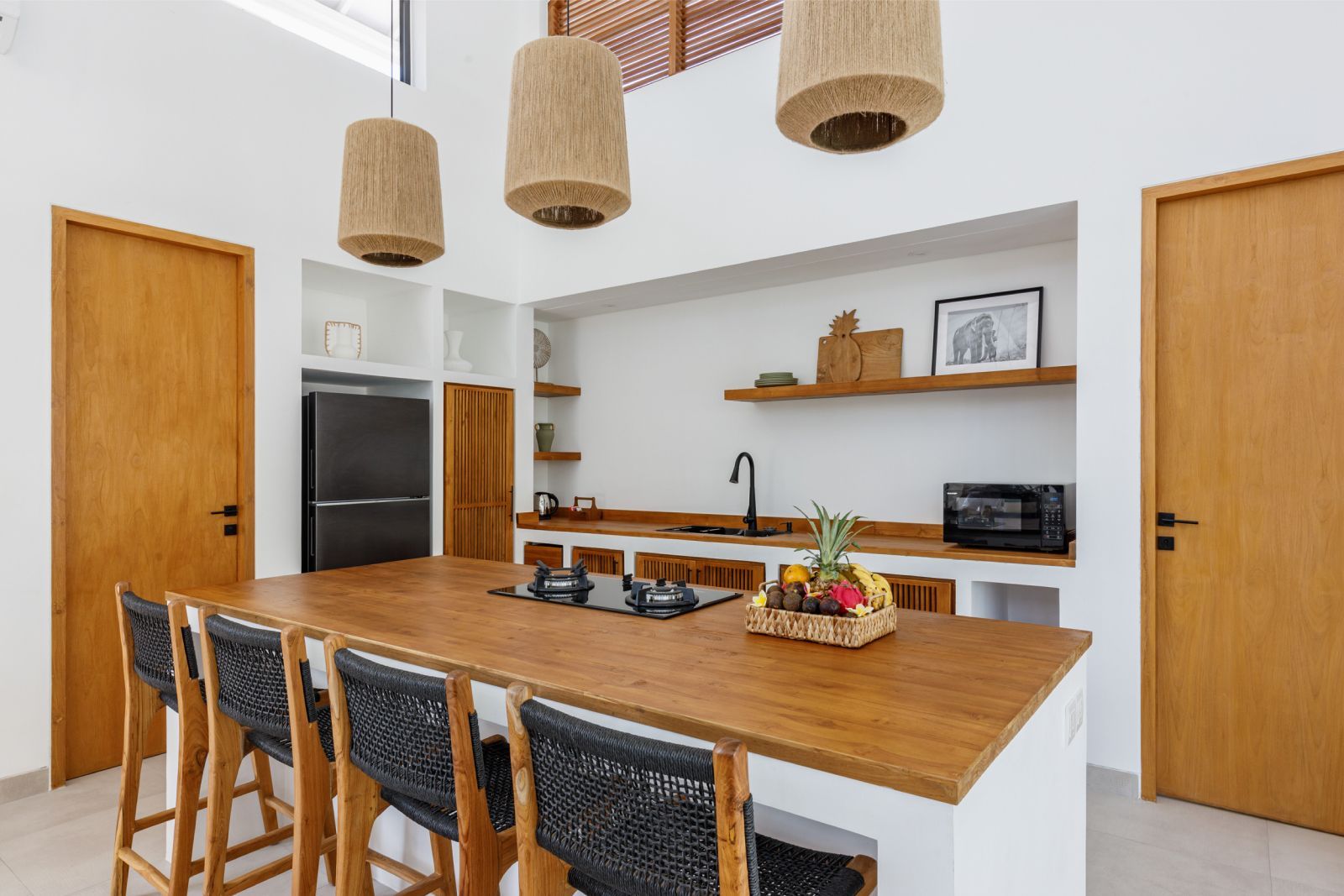 Modern kitchen with wood island, woven pendant lights, bar stools, and built-in appliances