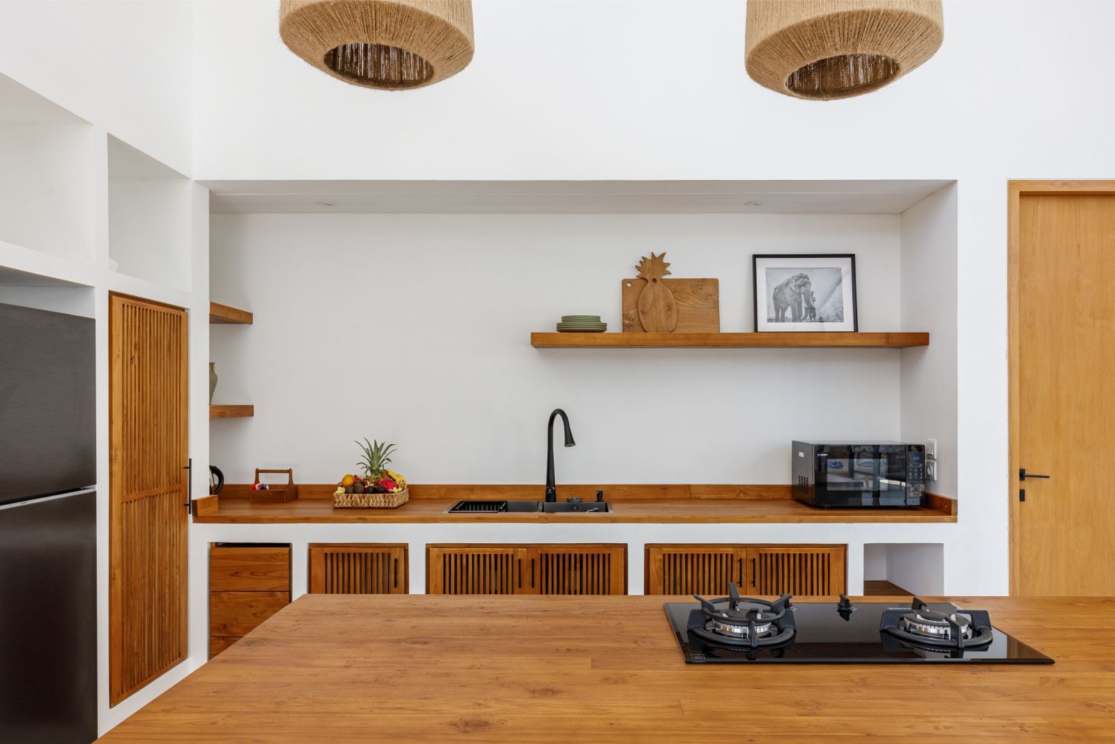 Modern kitchen with wood cabinets, island, sink, shelves, and woven pendant lights
