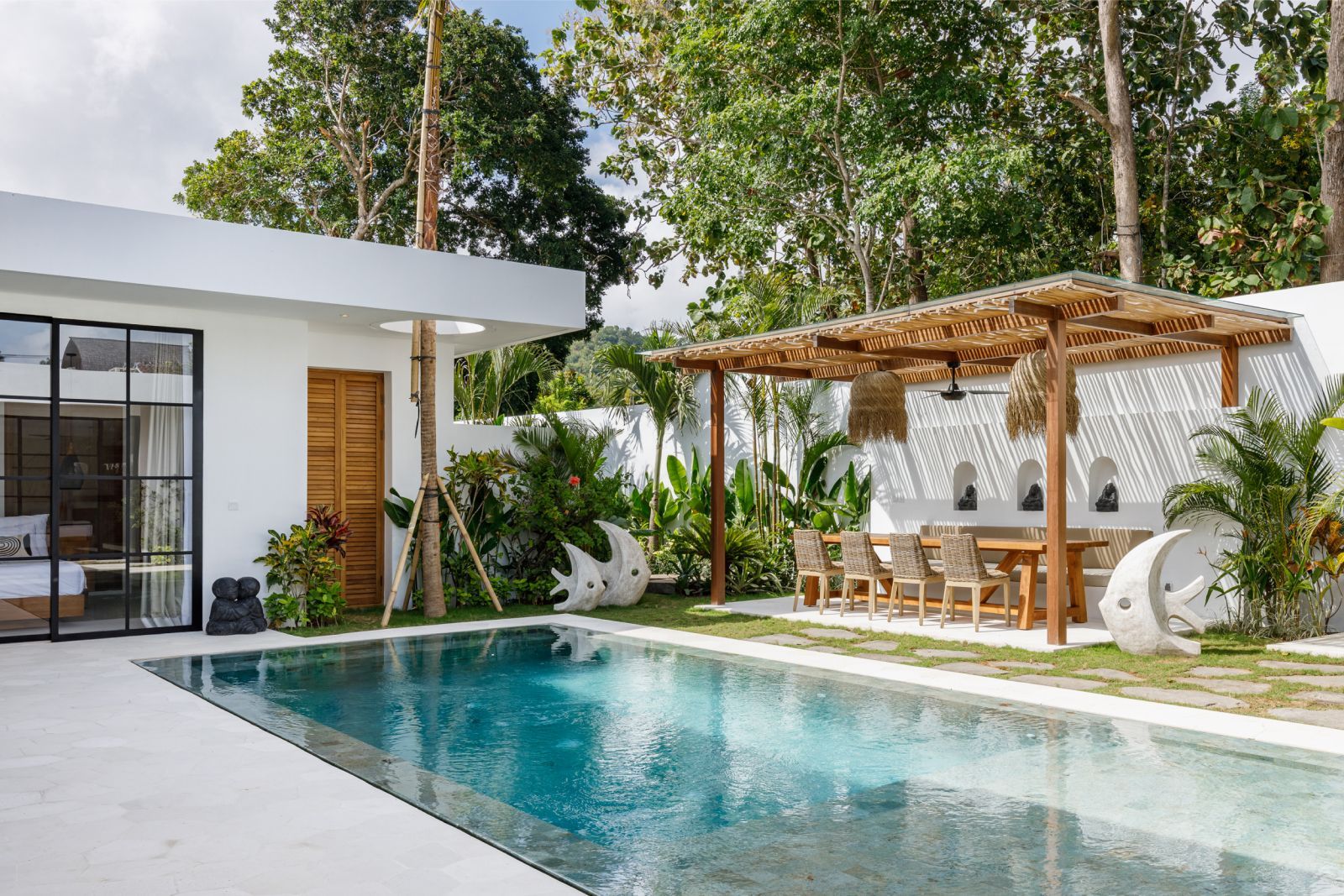 Modern villa pool with a thatched cabana and lush tropical landscaping