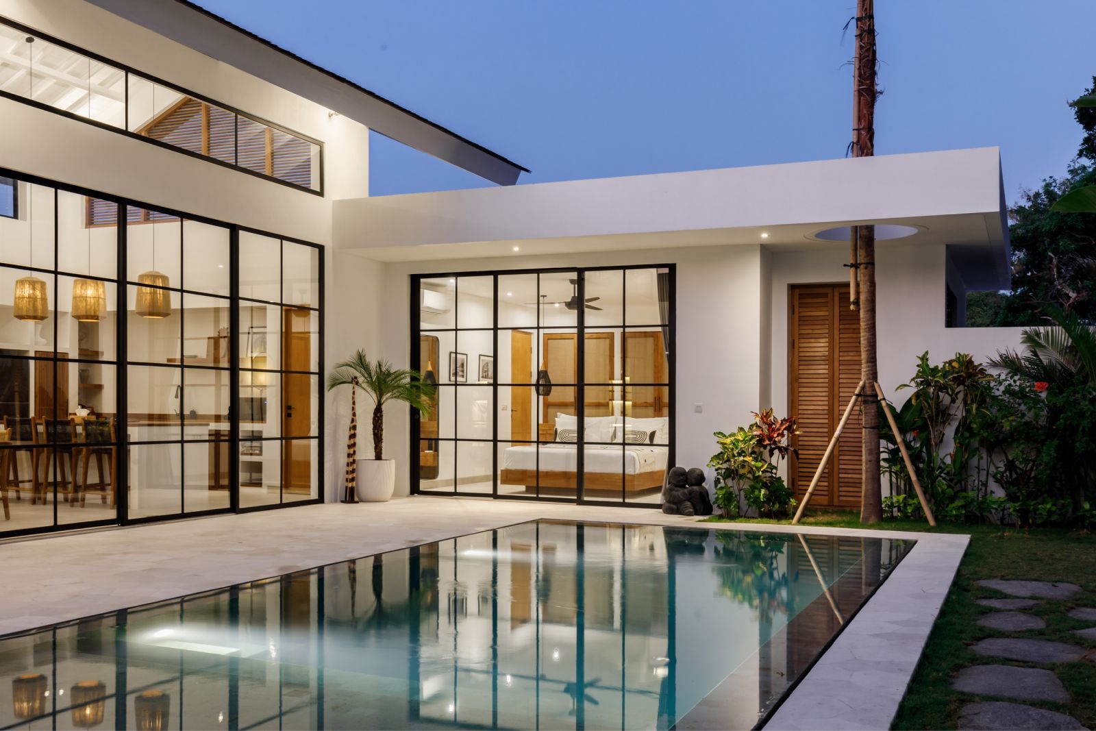 Modern house with glass walls and a reflecting pool at dusk