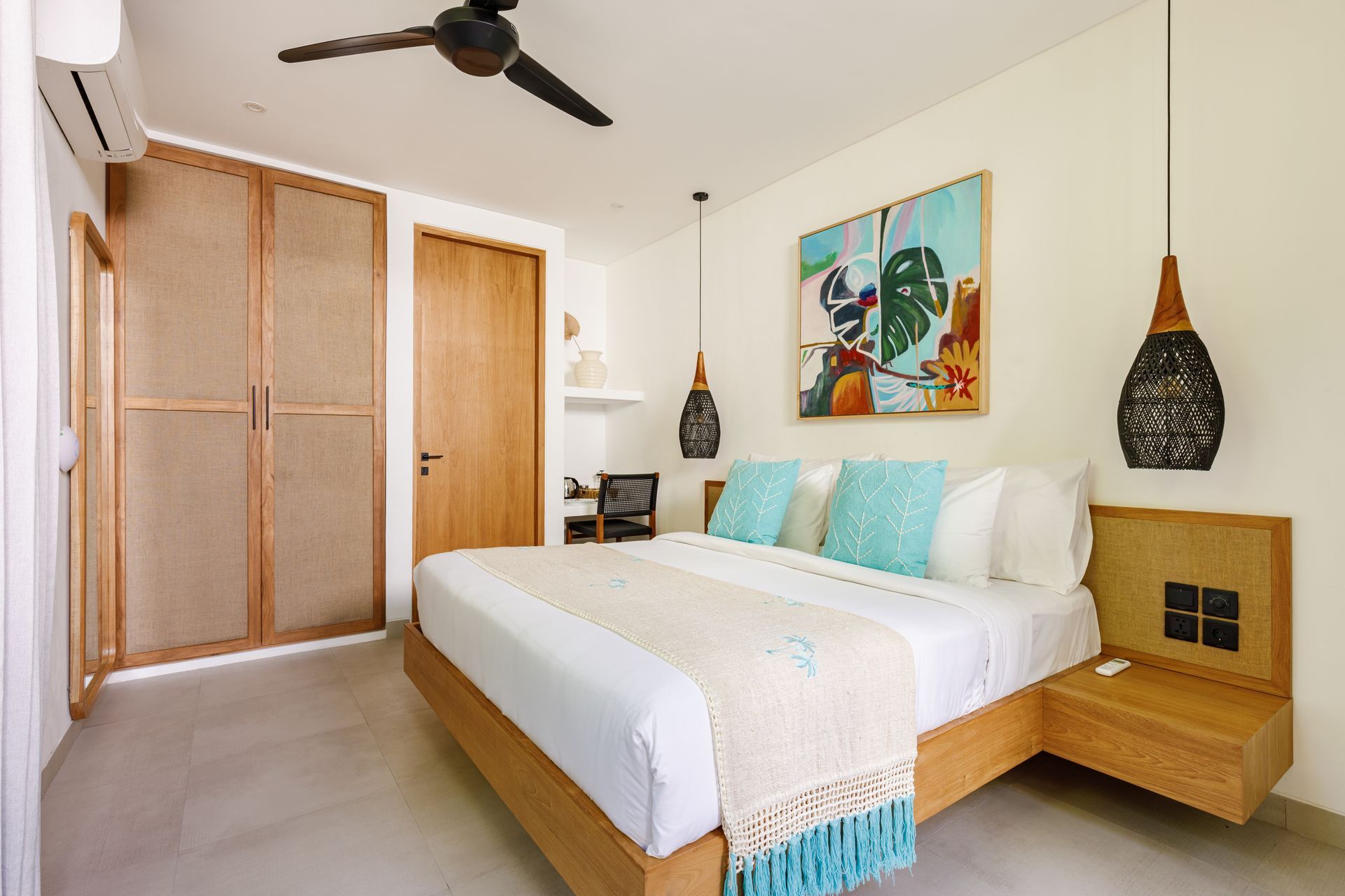 Bright bedroom with a wooden bed, white bedding, blue accents, wardrobe, and ceiling fan