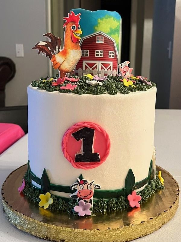 A birthday cake with a rooster and a cow on top of it.