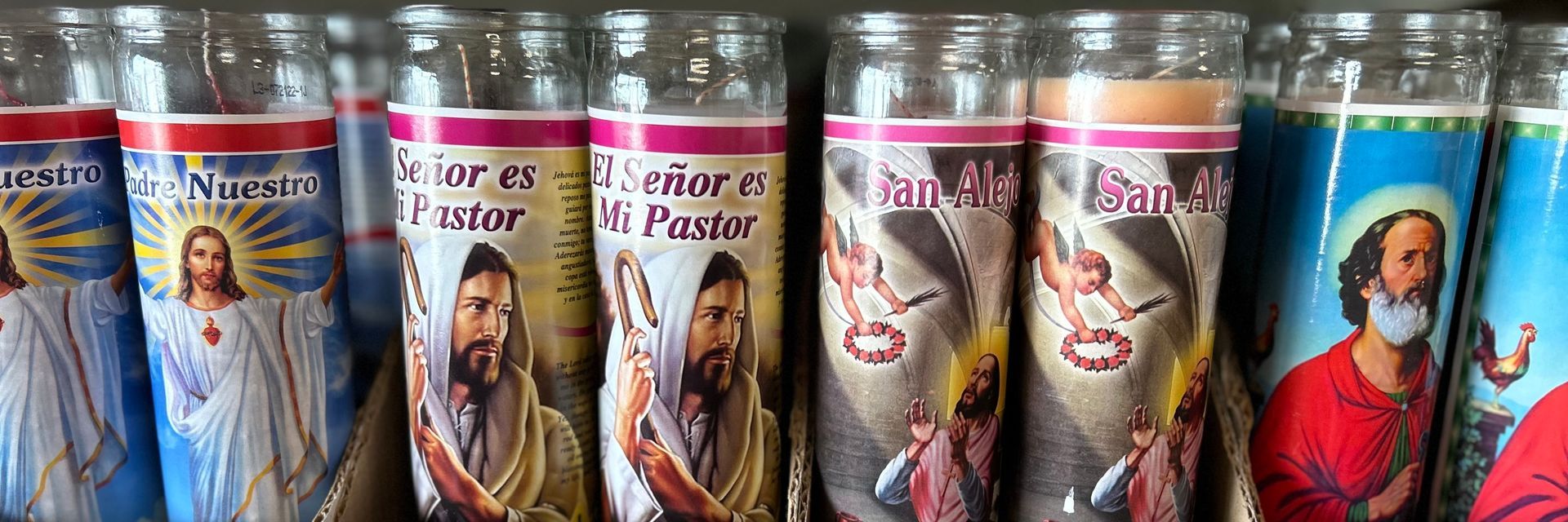 A row of candles with jesus and other saints on them